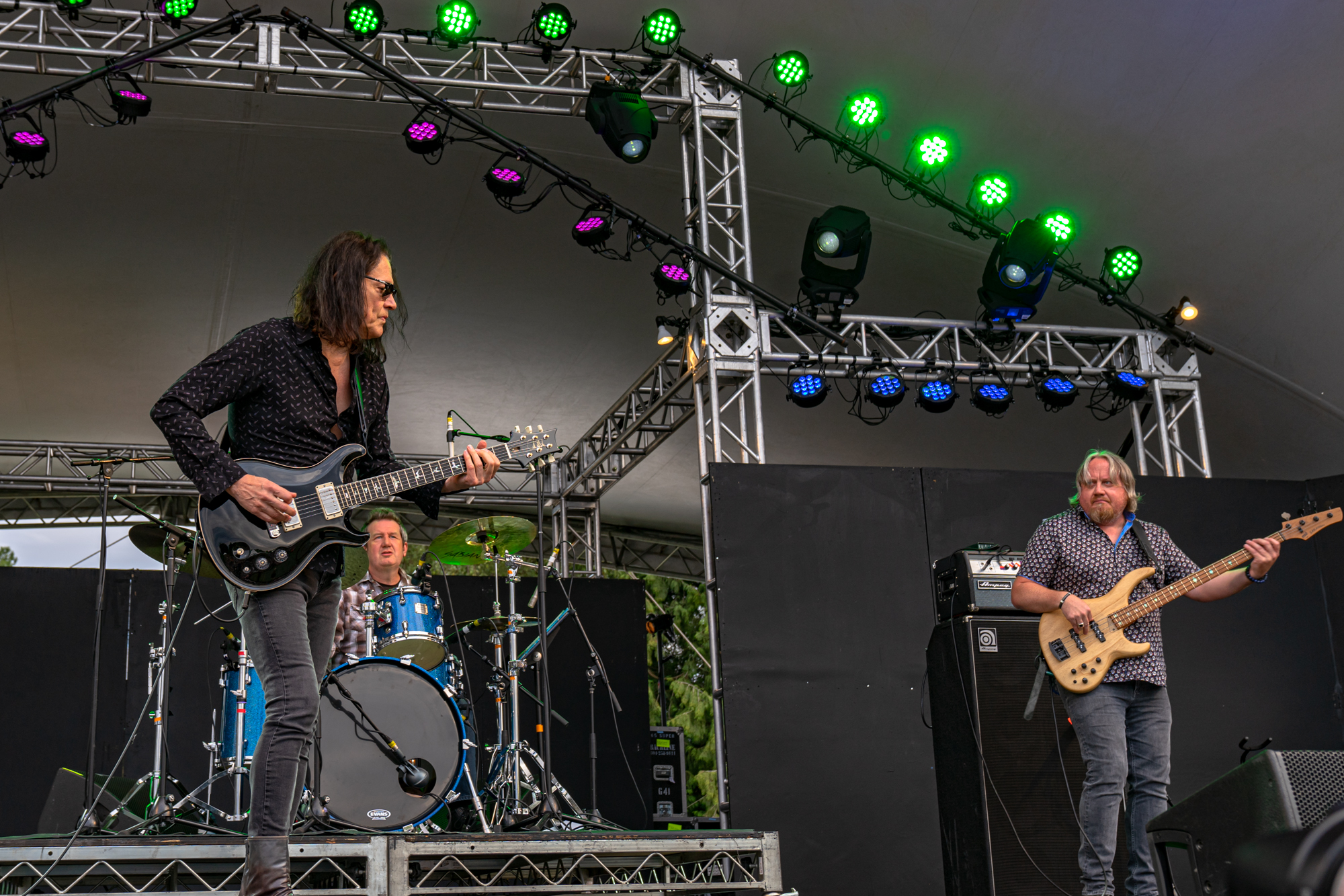 Robben Ford performing with his band on a stage lit with purple and green lights