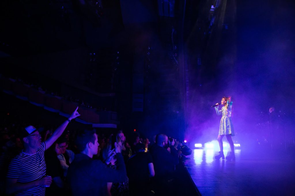 The band Chvrches performs on stage to a crowd in Vancouver