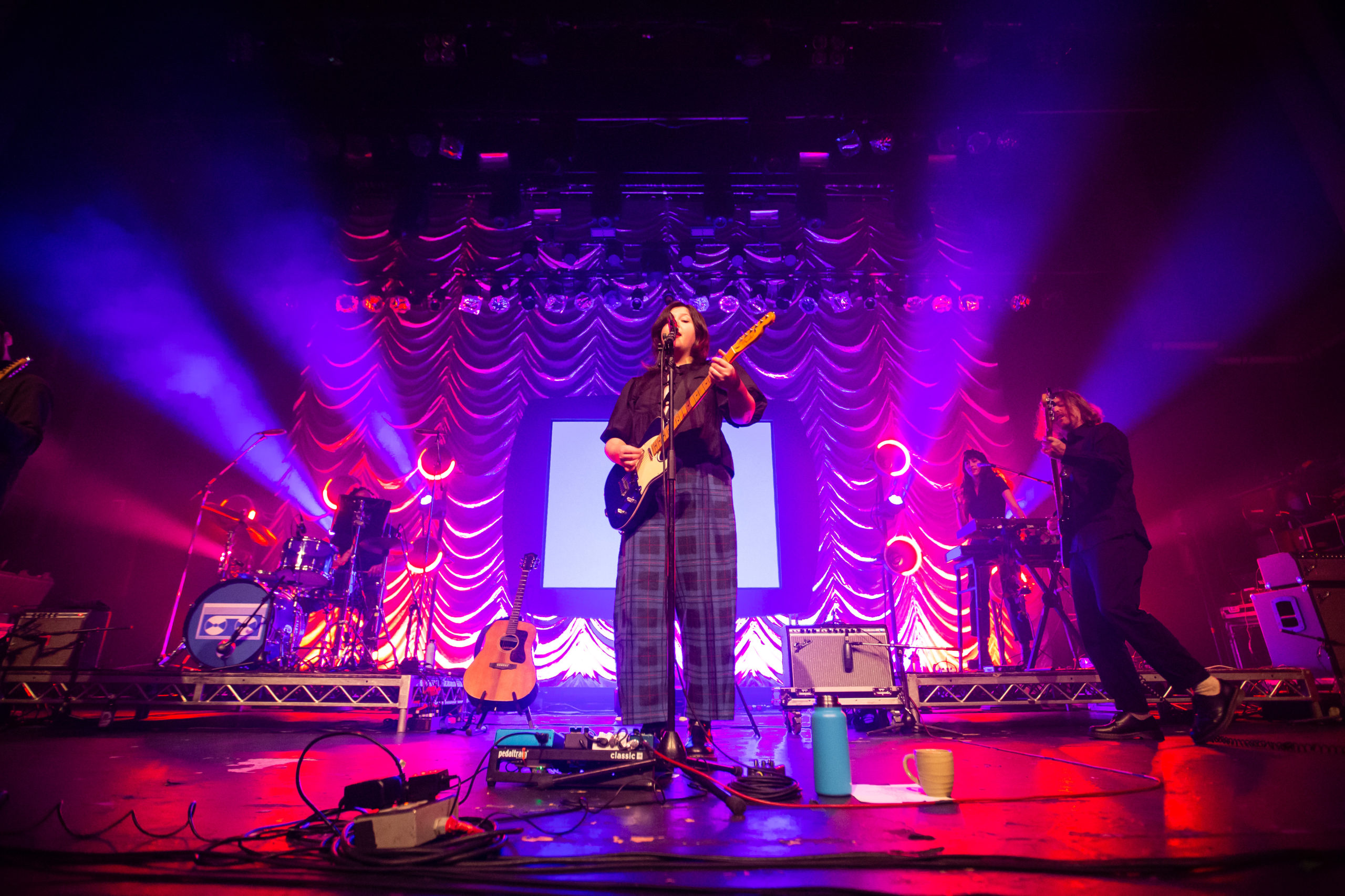 Lights cascade outward behind Lucy Dacus on the stage of the Vogue Theatre