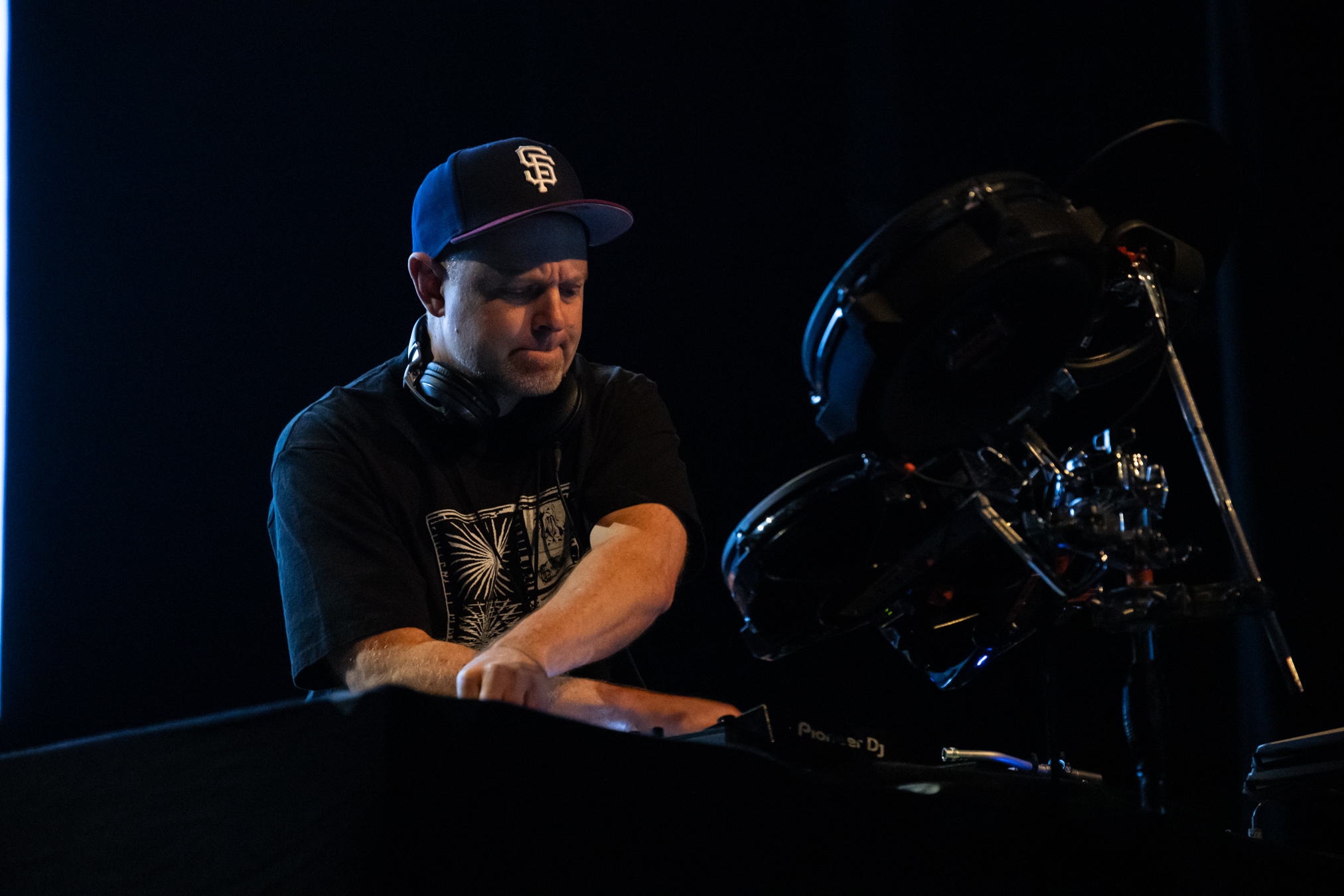 DJ Shadow is twisting knobs on the stage of the Vogue Theatre backlit by the massive projection screen.