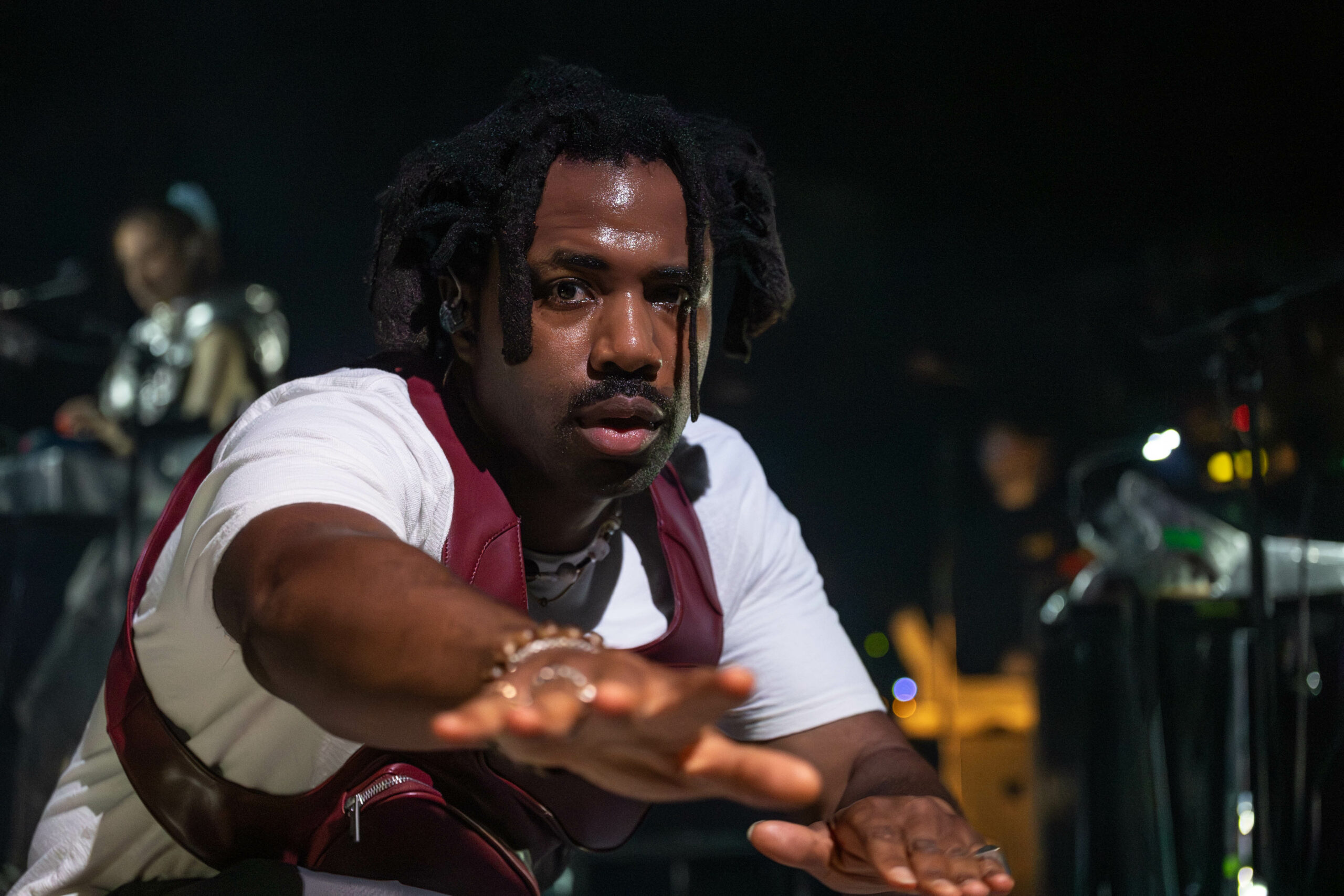 Sampha looks to the camera and gestures out with his hand