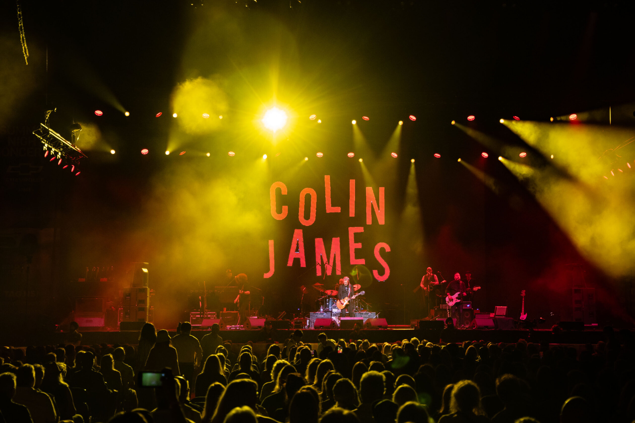 Colin James is on the stage of the Pacific Coliseum backed by his name on a giant screen and yellow lights shining on the crowd