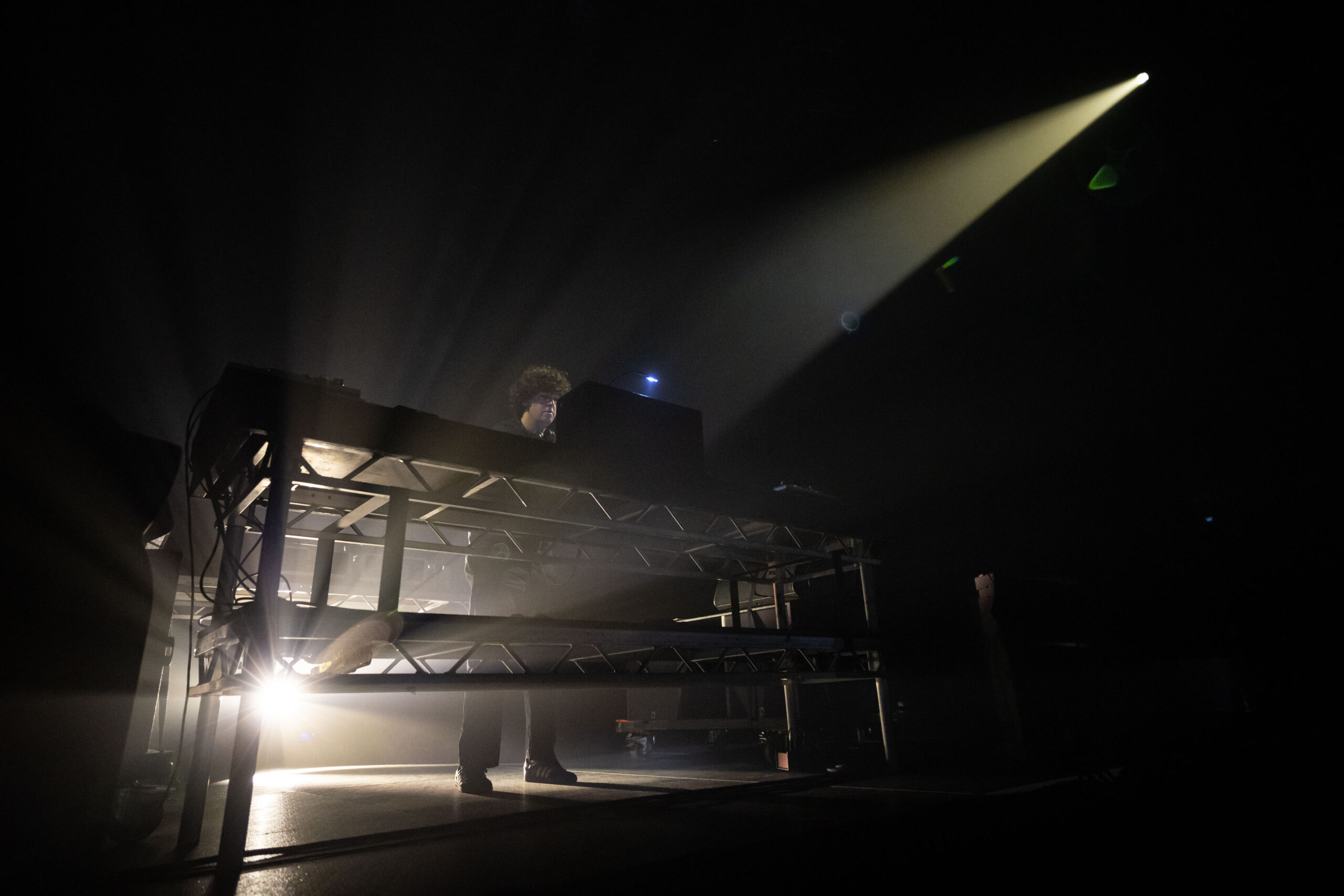 Jamie xx is on the stage at the Pacific Coliseum behind the DJ booth, backlit with misty light