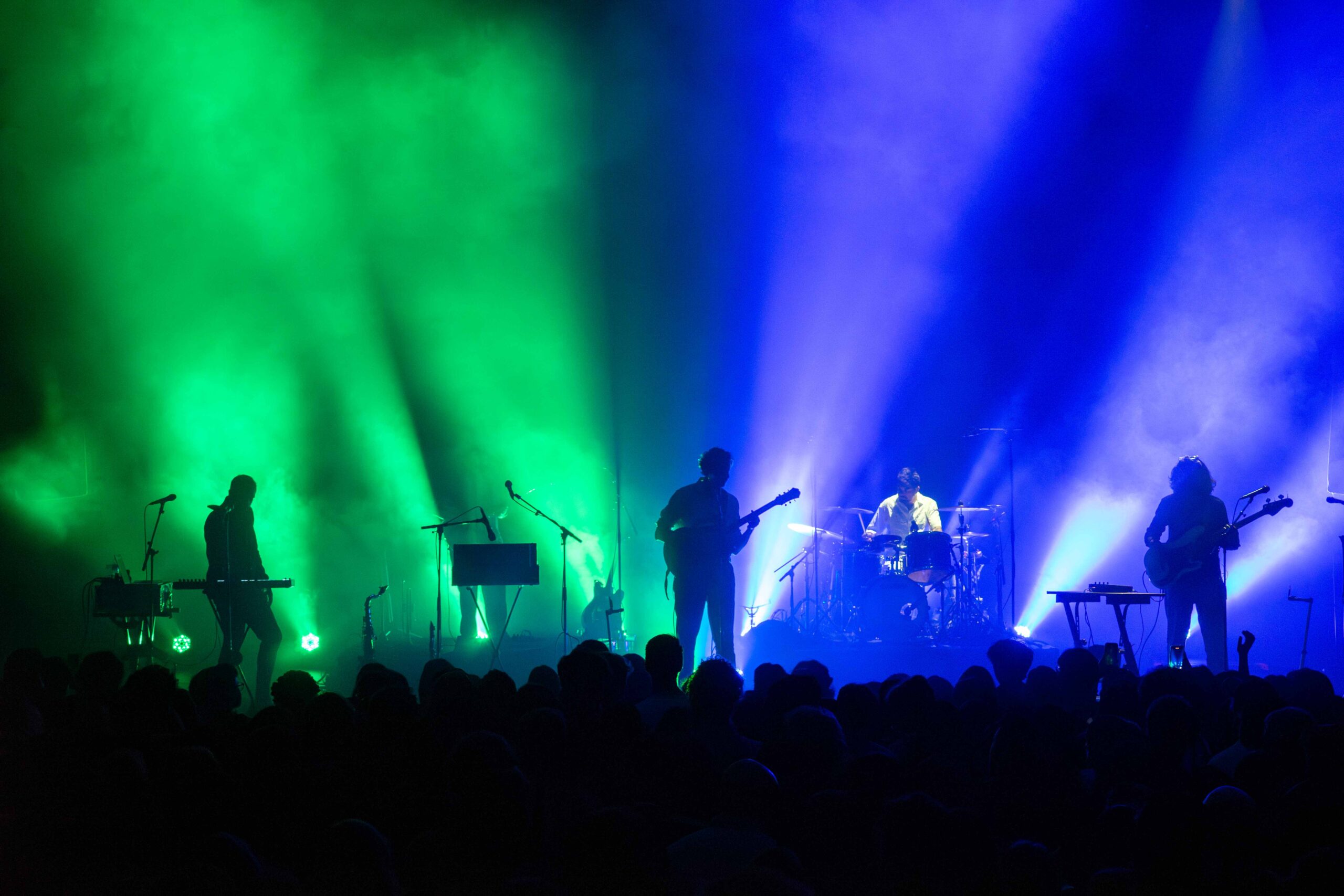 Peter Cat Recording Co. on stage with green and blue backing lights behind them
