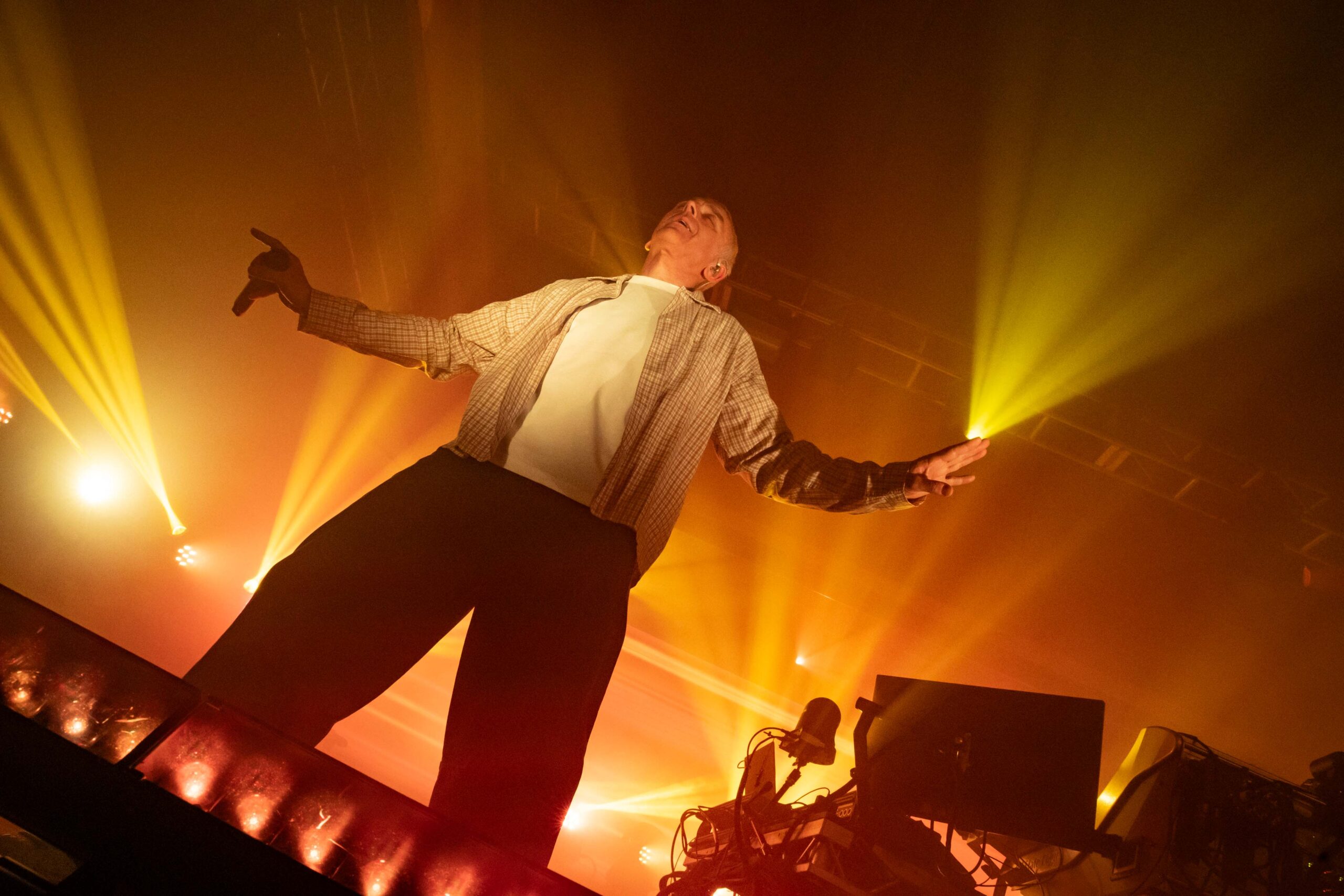 Carl Hyde dances on the stage of the Showbox SoDo with starbusts of yellow and orange light all around him, looking up at the ceiling with his arms out